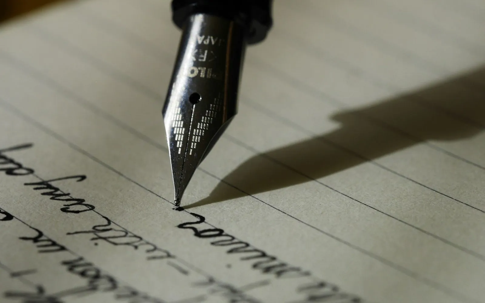 Hand writing a cover letter with a pen at a desk