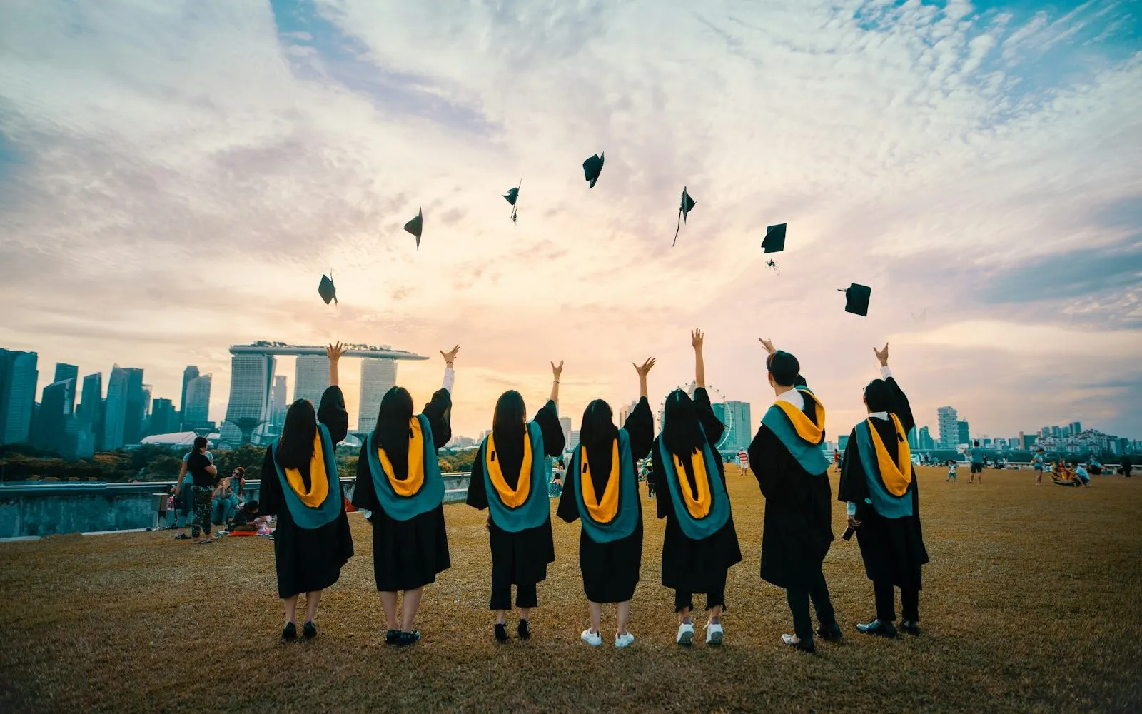 Graduation caps tossed into the air against a bright sky